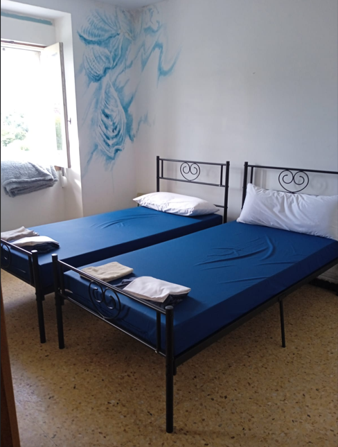 Comfortable bedroom with two single beds, blue mattresses and artistic wall mural